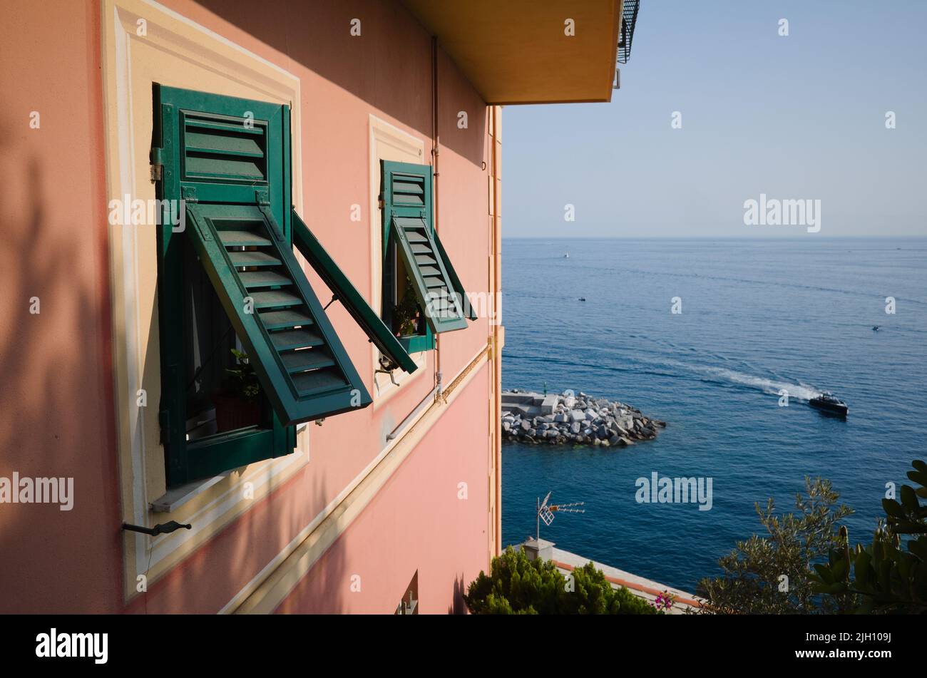 Pink building facade with green shutters on windows in typical Italian style. Traditional italian house on Mediterranean shore, Camogli, Liguria Stock Photo