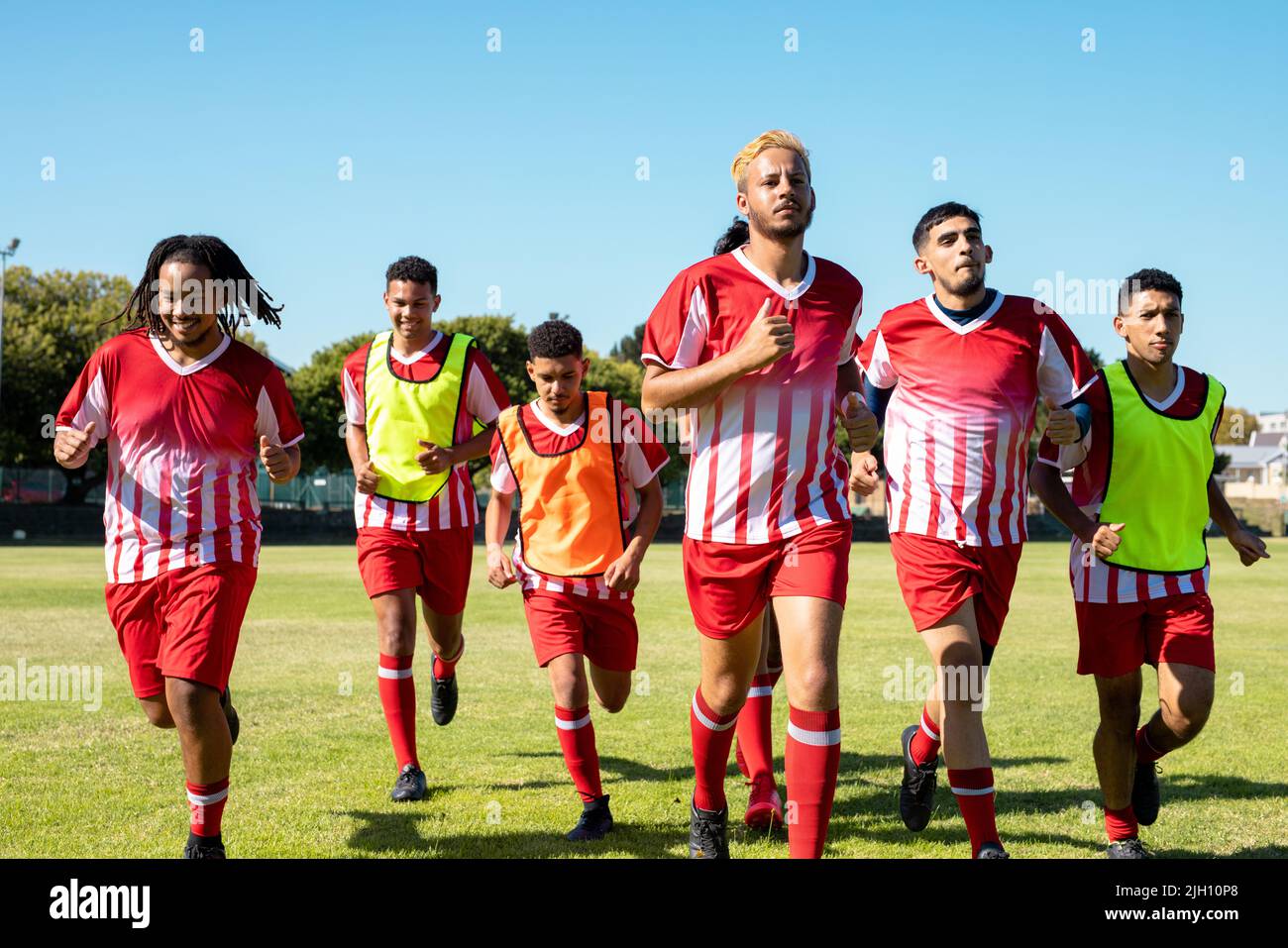 Multiracial male athletes wearing red sports uniforms running in