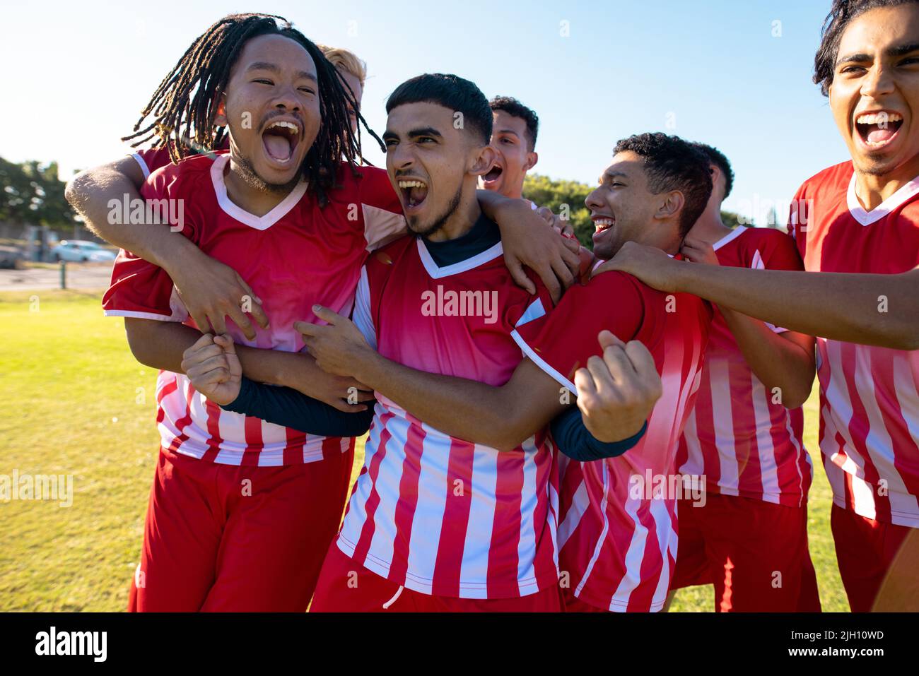 Multiracial male team players screaming while celebrating victory after soccer match at playground Stock Photo