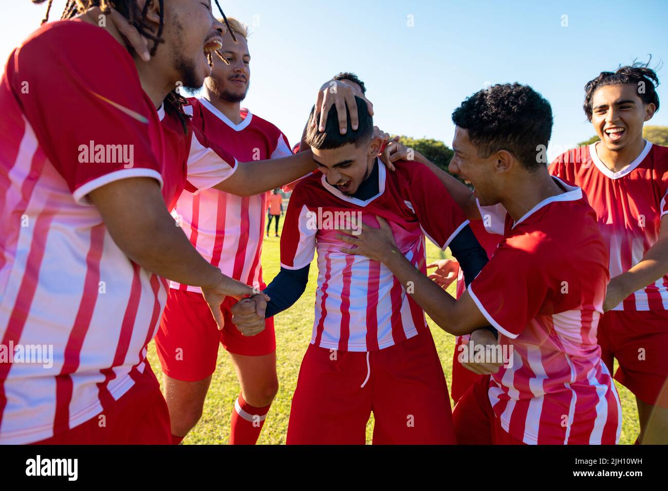 Multiracial male soccer team screaming while celebrating goal during match at playground Stock Photo