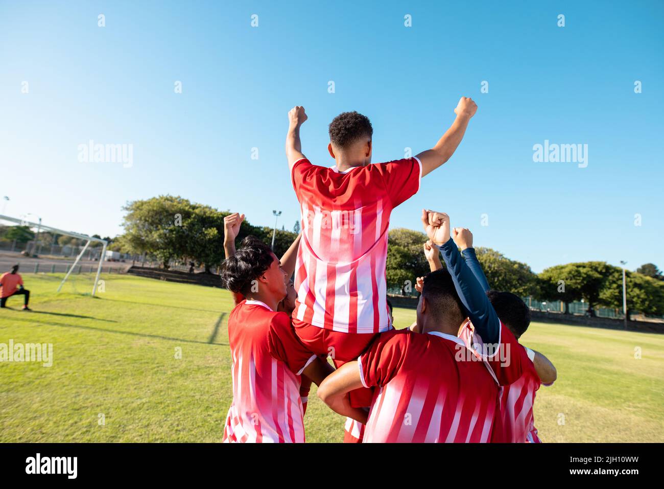 Rear view of multiracial players carrying cheerful teammate on shoulders while celebrating goal Stock Photo