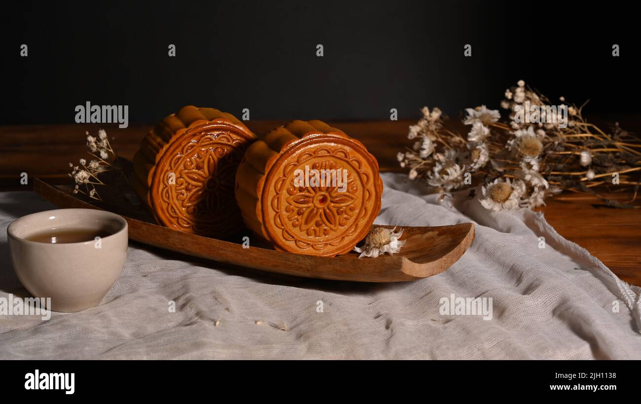 Traditional mooncakes on wooden table setting with teacup. Mid Autumn ...