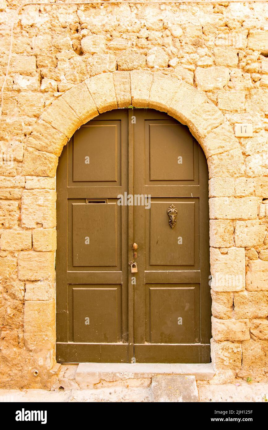 The facade of an ancient stone house with a wooden door on the ...