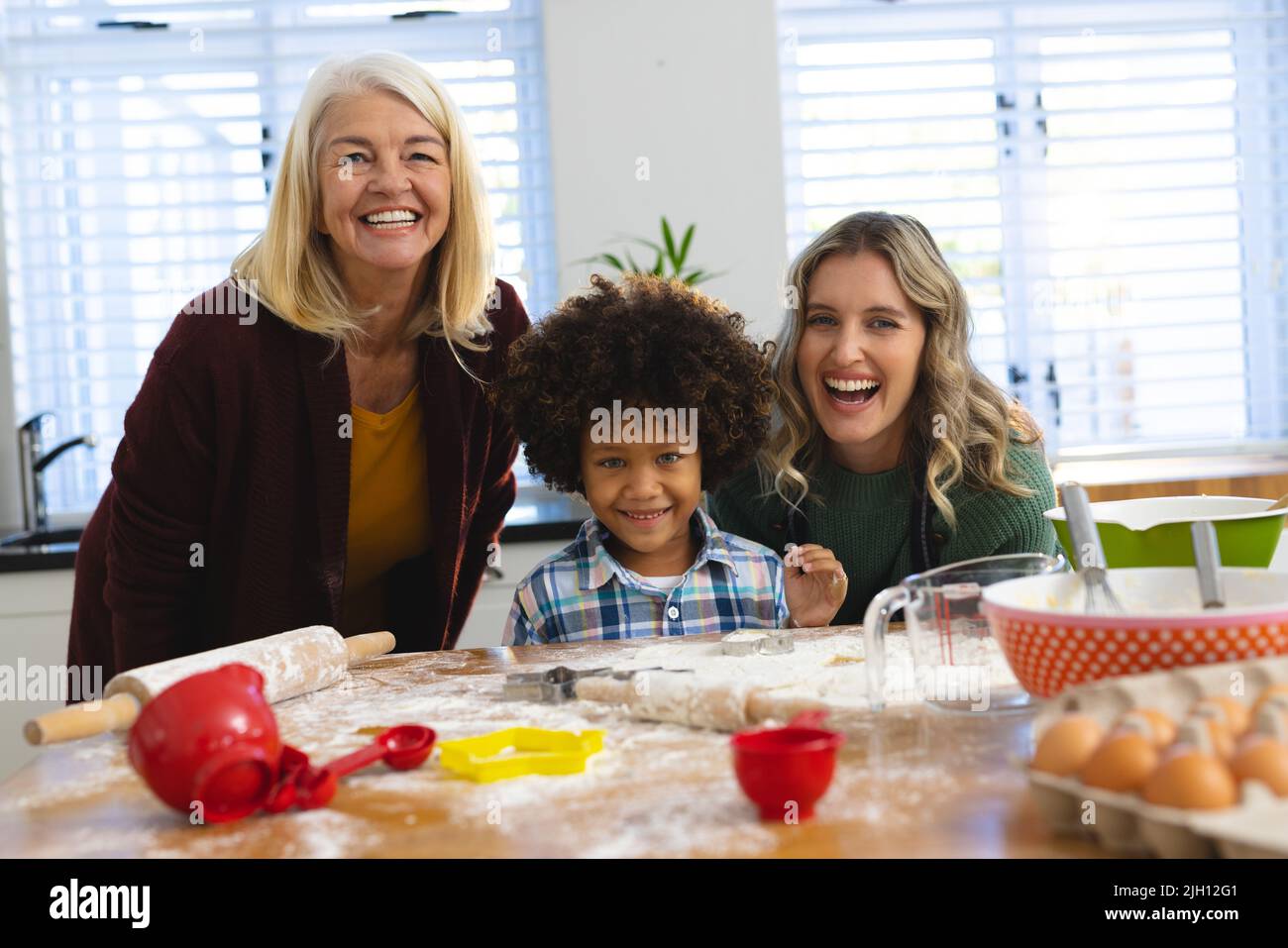 Portrait of cheerful multiracial multigeneration family preparing food on messy table in kitchen Stock Photo