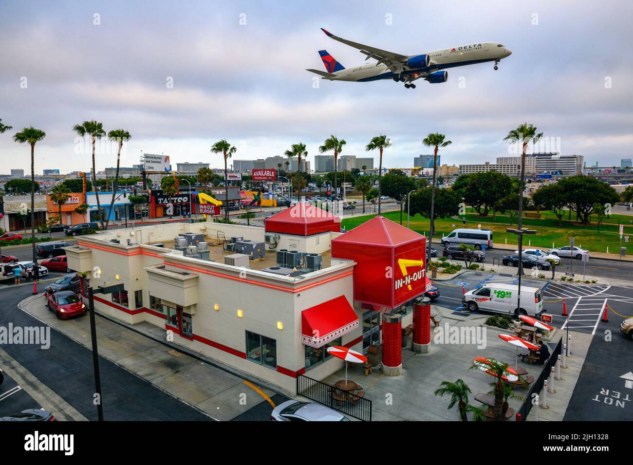 Delta Airlines plane flies above In-N-Out Burger restaurant while landing at the Los Angeles International Airport LAX Stock Photo