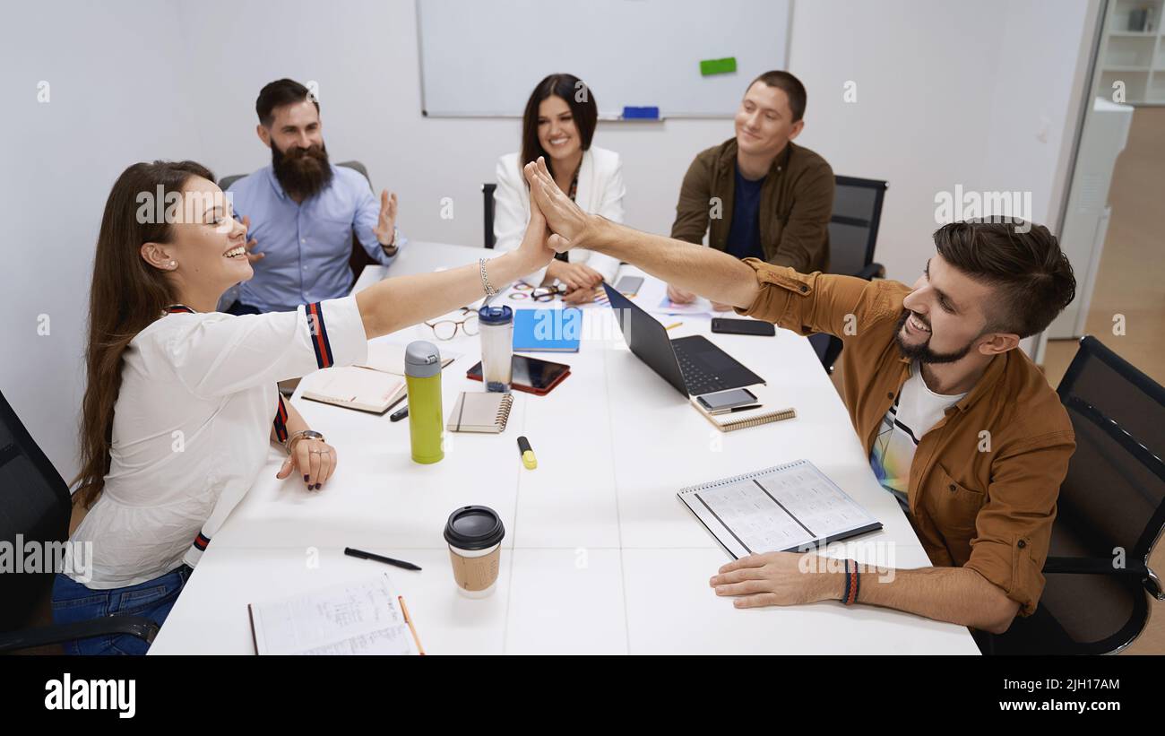 Happy team giving hightfive. Celebrating success with hi five. Coworkers friends touching hands after completed the work perfectly. Stock Photo