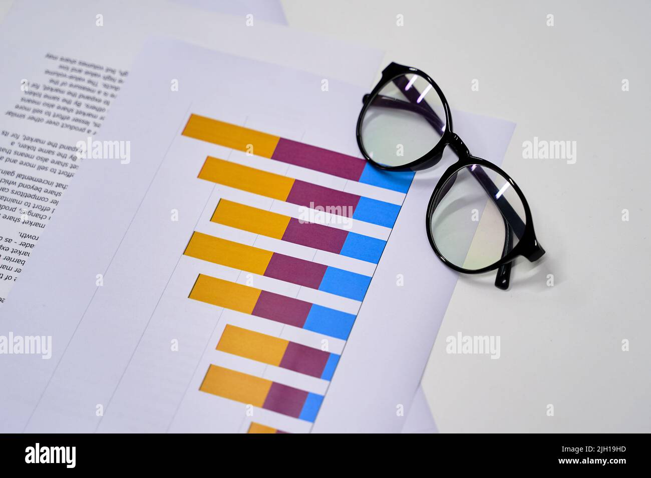 Stylish eyeglasses and colorful chart on the white work table. Business concept. Stock Photo
