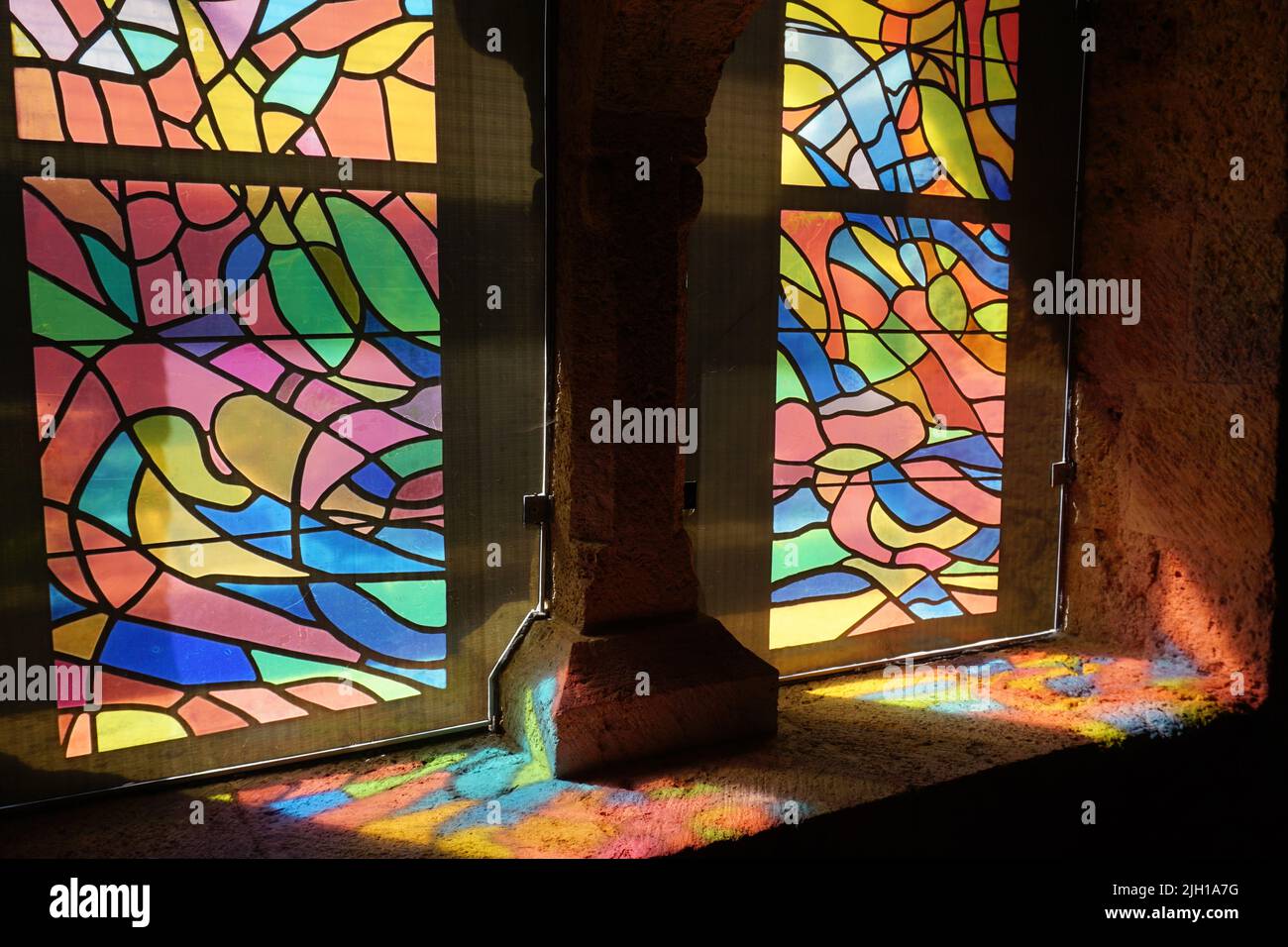 sun rays through colorful stained glass windows of a church appearing on the stone ground Stock Photo