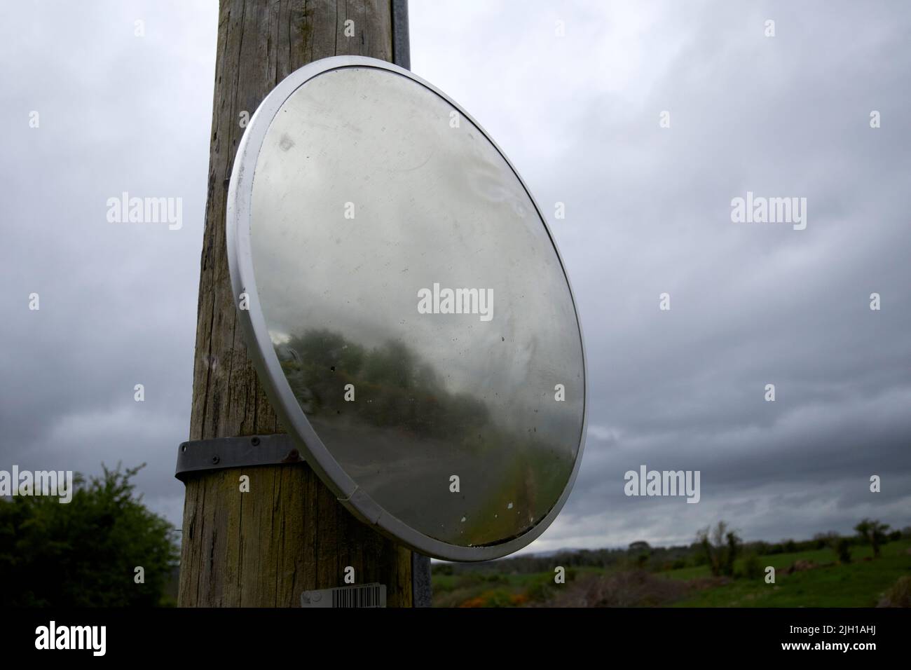 convex mirror used at the exit of a property on a tight country lane in Castlebar county mayo republic of ireland Stock Photo