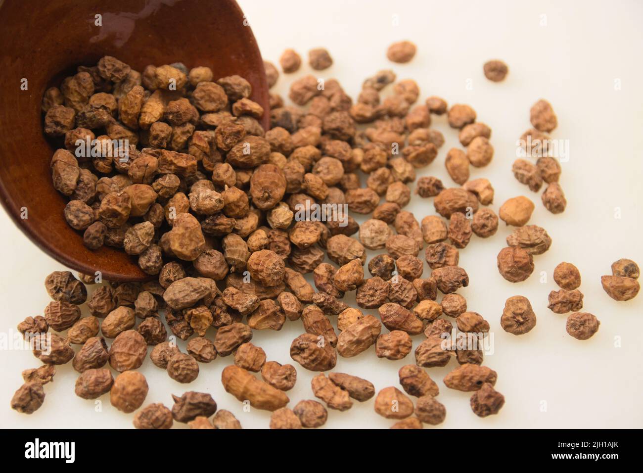 Close-up of a bunch of dried tiger nuts (cyperus esculentus) scattered on a white table with copy space Stock Photo