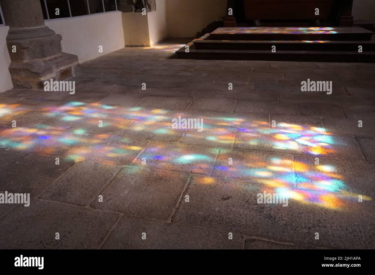 sun rays through colorful stained glass windows of a church appearing on the stone ground Stock Photo