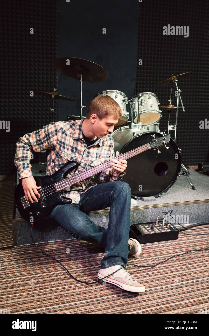 Bass guitar player sitting near drum set Stock Photo Alamy