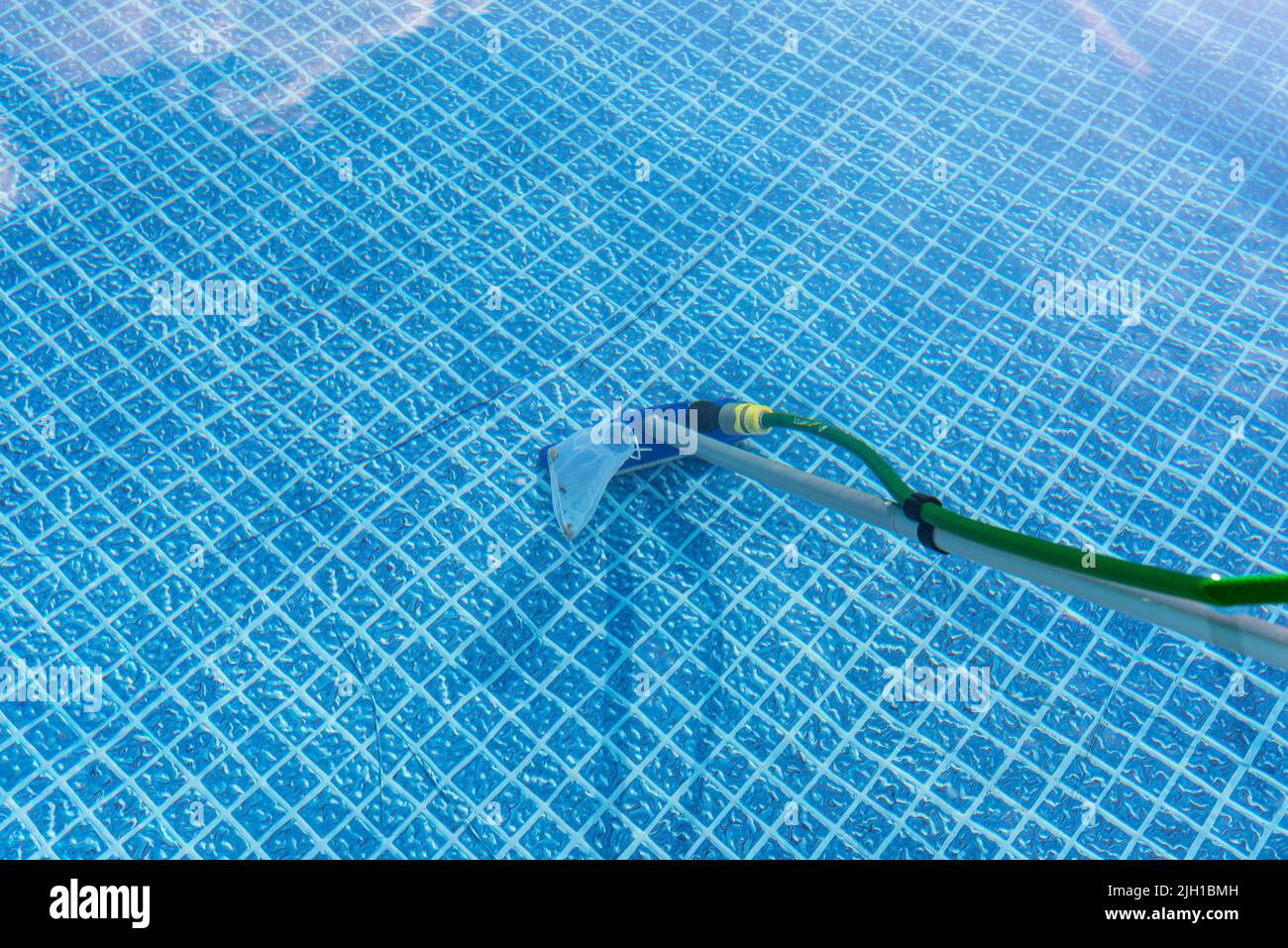 Cleaning the home pool in the garden with a brush, dragging dirt from