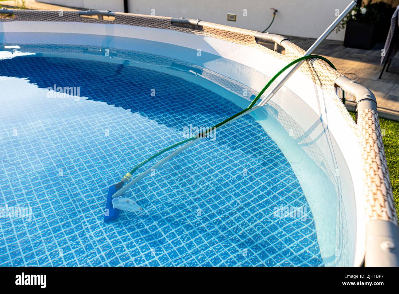 Cleaning the home pool in the garden with a brush, dragging dirt from