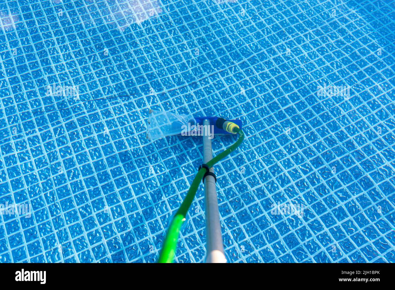 Cleaning the home pool in the garden with a brush, dragging dirt from