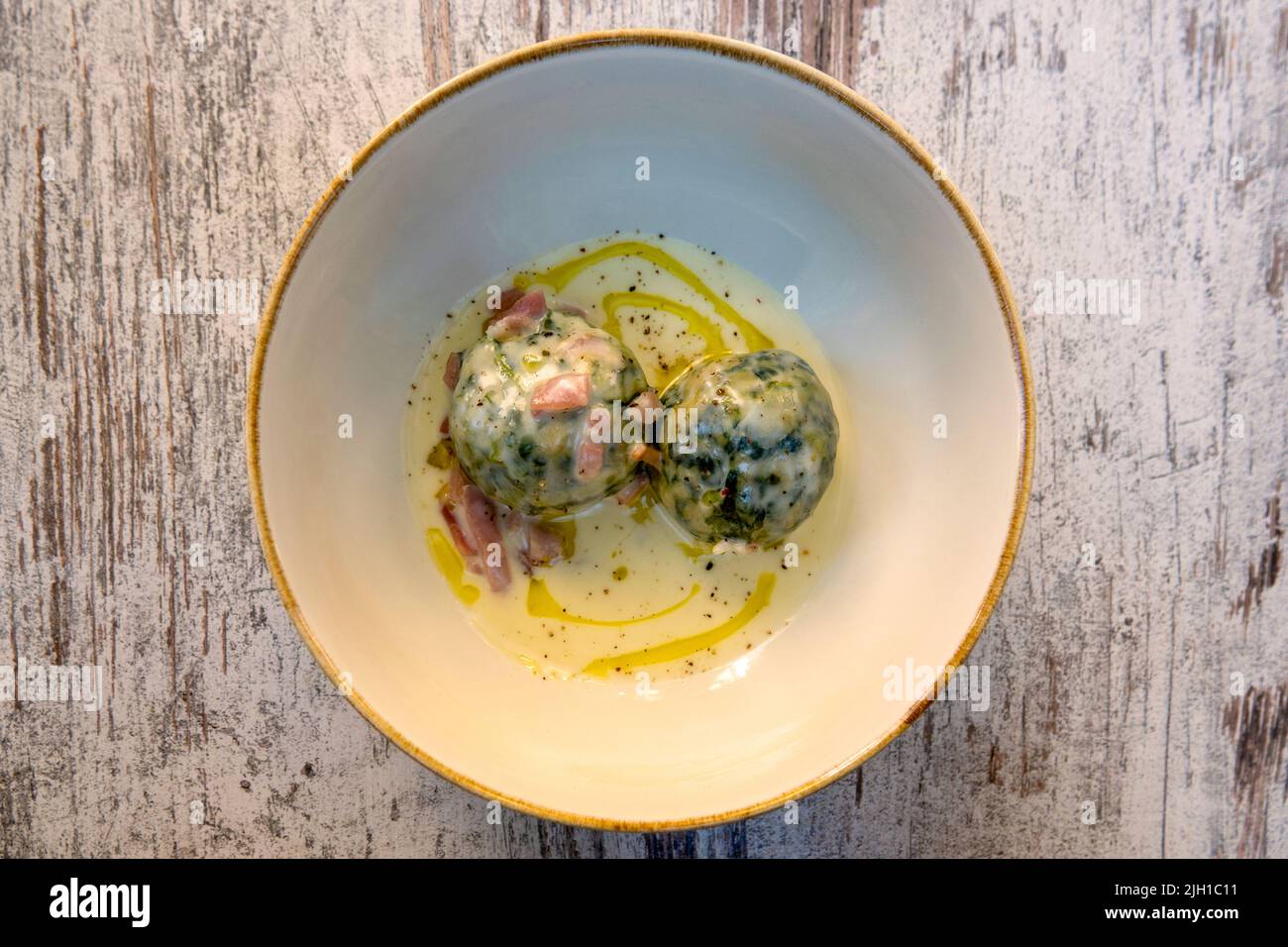 Traditional Tyrolean spinach knödel with cream cheese and speck Stock Photo