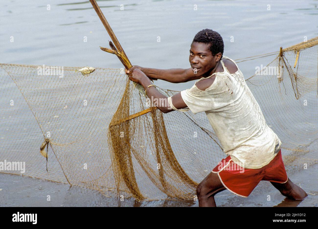 Uganda, Mbarara; Man checking the fishing nets in a fish pond Stock