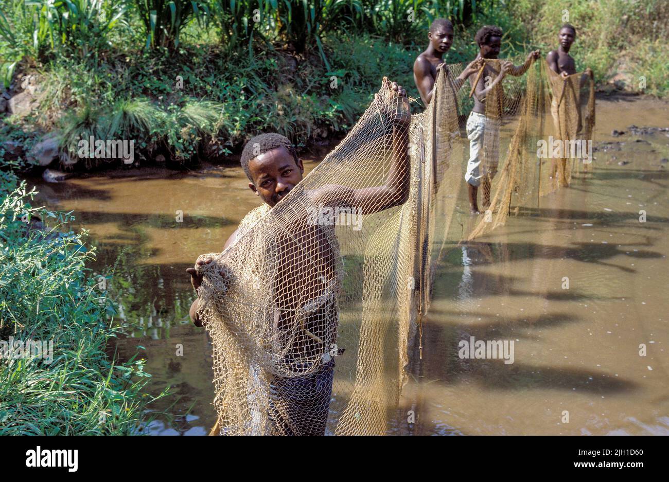 Uganda, Mbarara; Men checking the fishing nets in a fish pond Stock