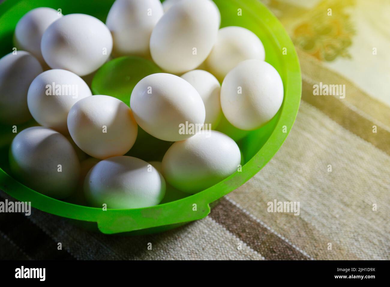 assorted white eggs grouped in green bowl on table and soft side lighting Stock Photo