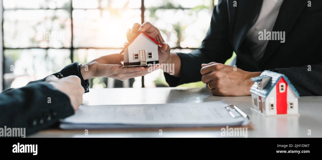 real estate agent holding house model to his client after signing ...