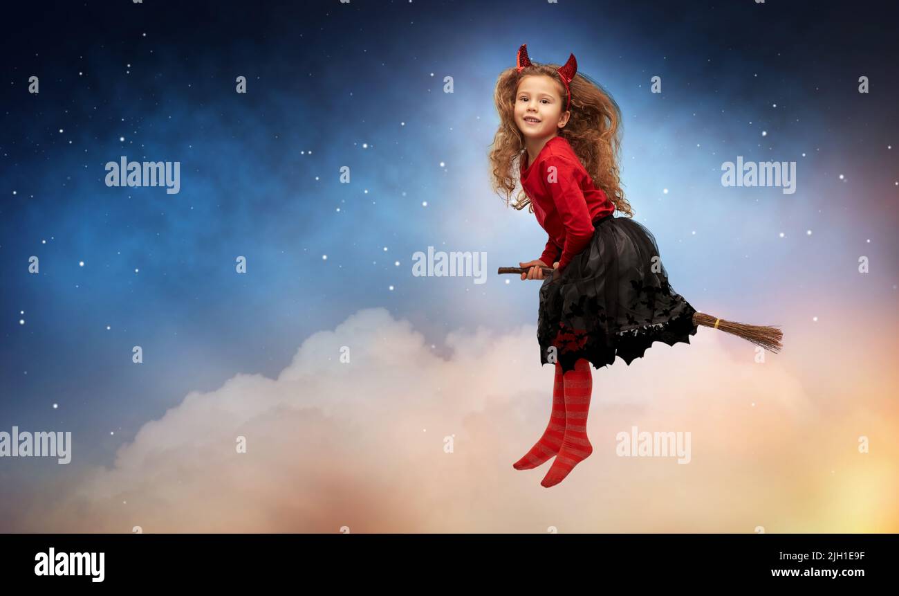 girl in halloween costume flying on witch's broom Stock Photo