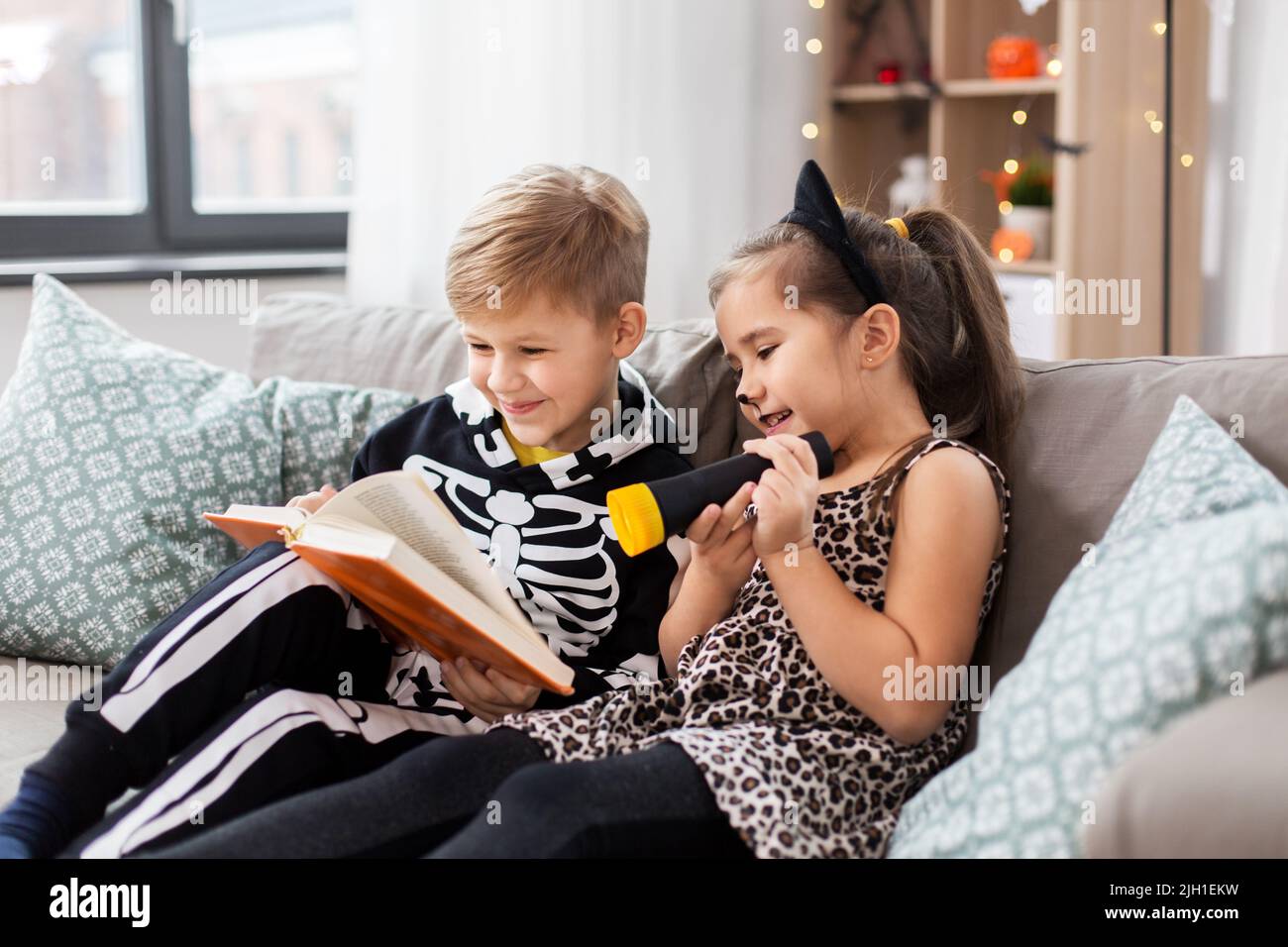 kids in halloween costumes reading book at home Stock Photo Alamy
