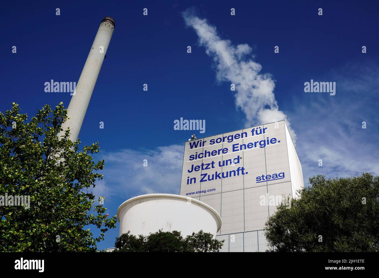 Herten Germany, July 14, 2022: Inscription *'We ensure safe energy. Now and in the future'* on a block of the STEAG cogeneration plant in Herten promises safe energy for the future through hard coal. The Herne combined heat and power plant only has one block in which not only electricity but also district heating for the Ruhr district heating network is generated from hard coal. Stock Photo