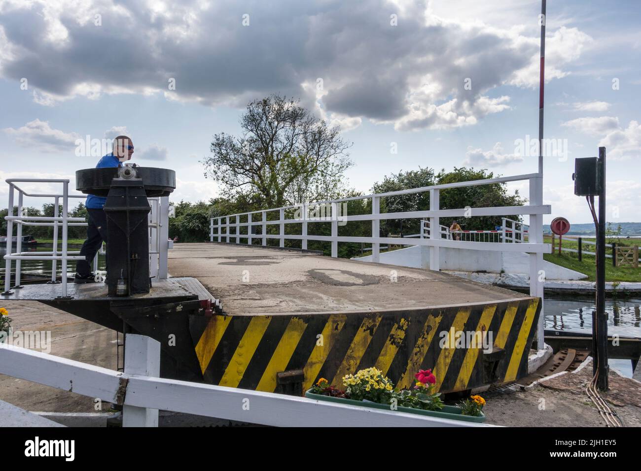 Canal guard swinging Splatt Bridge for boat to pass, Frampton on Severn, Gloucestershire, UK Stock Photo