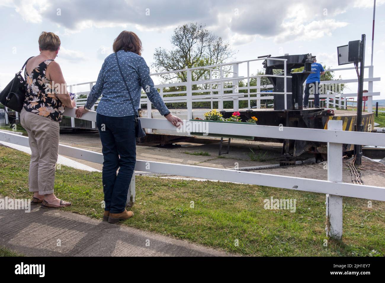 Two women watching warden swinging Splatt Bridge, Frampton on Severn, Gloucestershire, UK Stock Photo