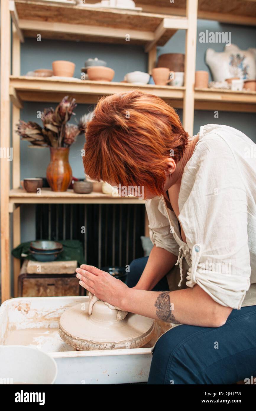 Potter work on potters wheel sideview. Closeup of potter working on ...