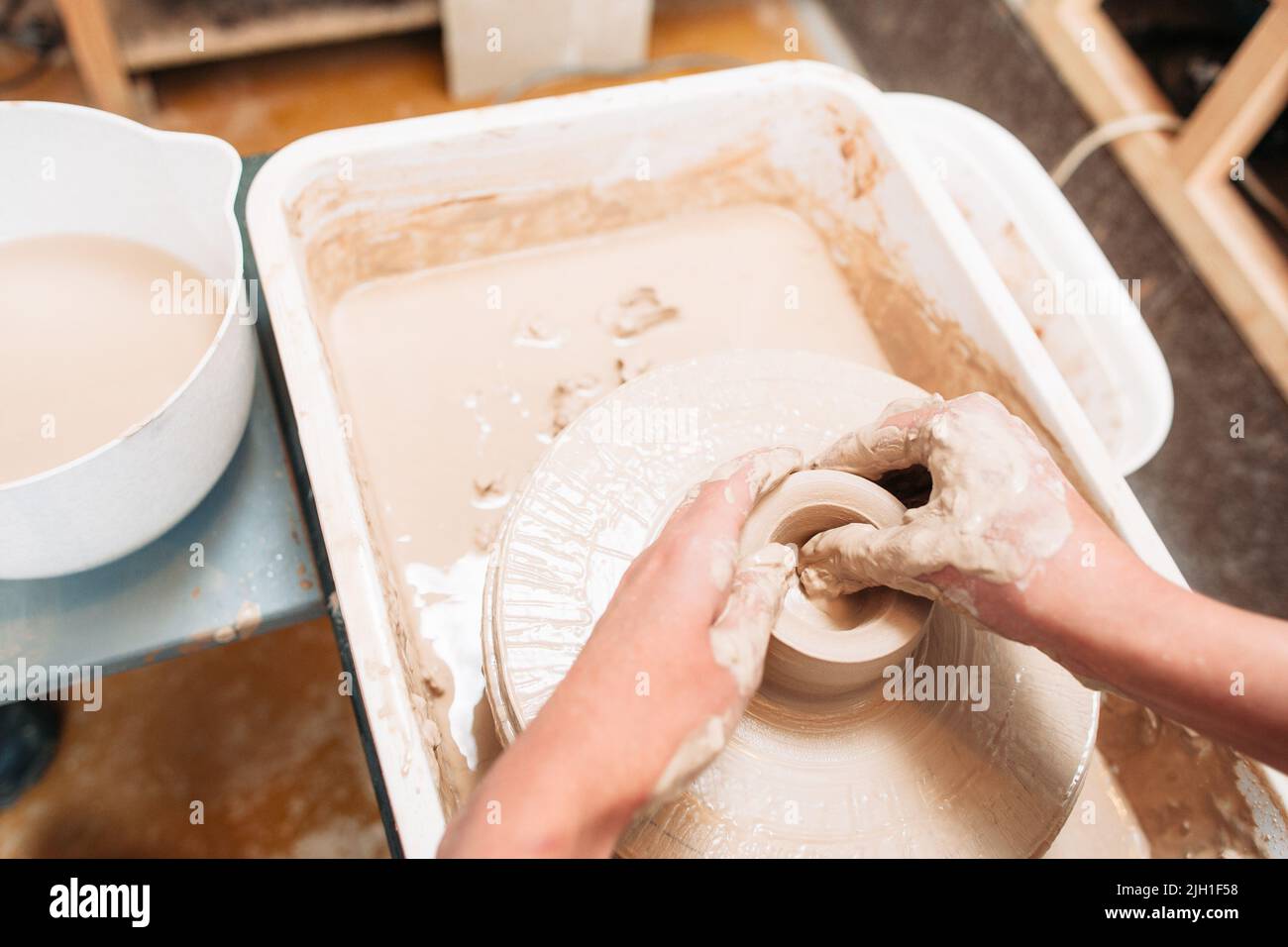 Artist makes pottery bottom on potters wheel. Hands of potter mold