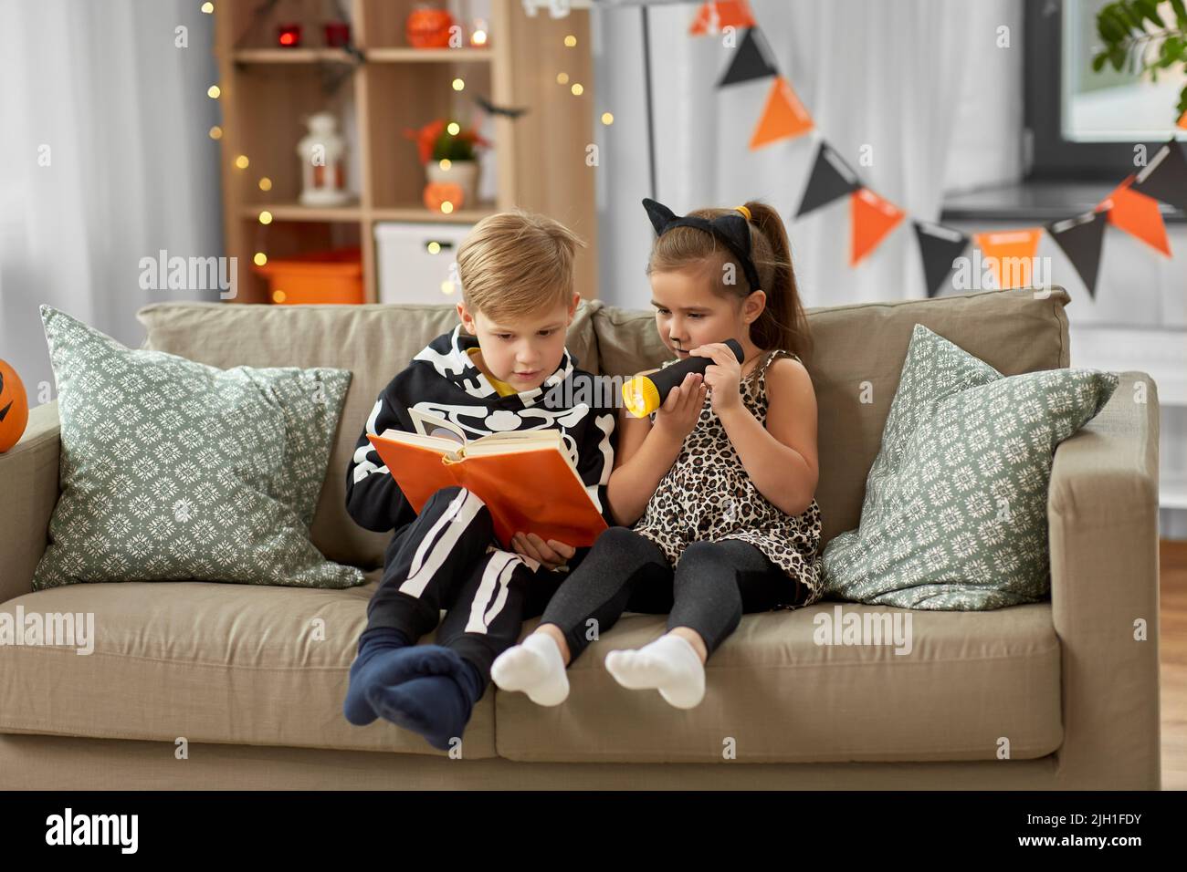 kids in halloween costumes reading book at home Stock Photo Alamy