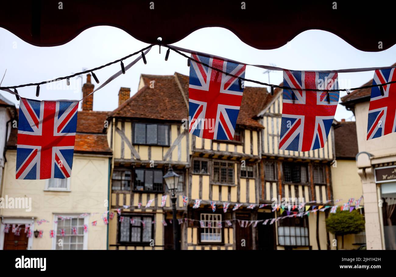 Thaxted Essex England Union Jack Flags and old buildings July 2022 Union Jack flags flutter in front of Dick Turpins House and the 14th century Guildhall Stock Photo