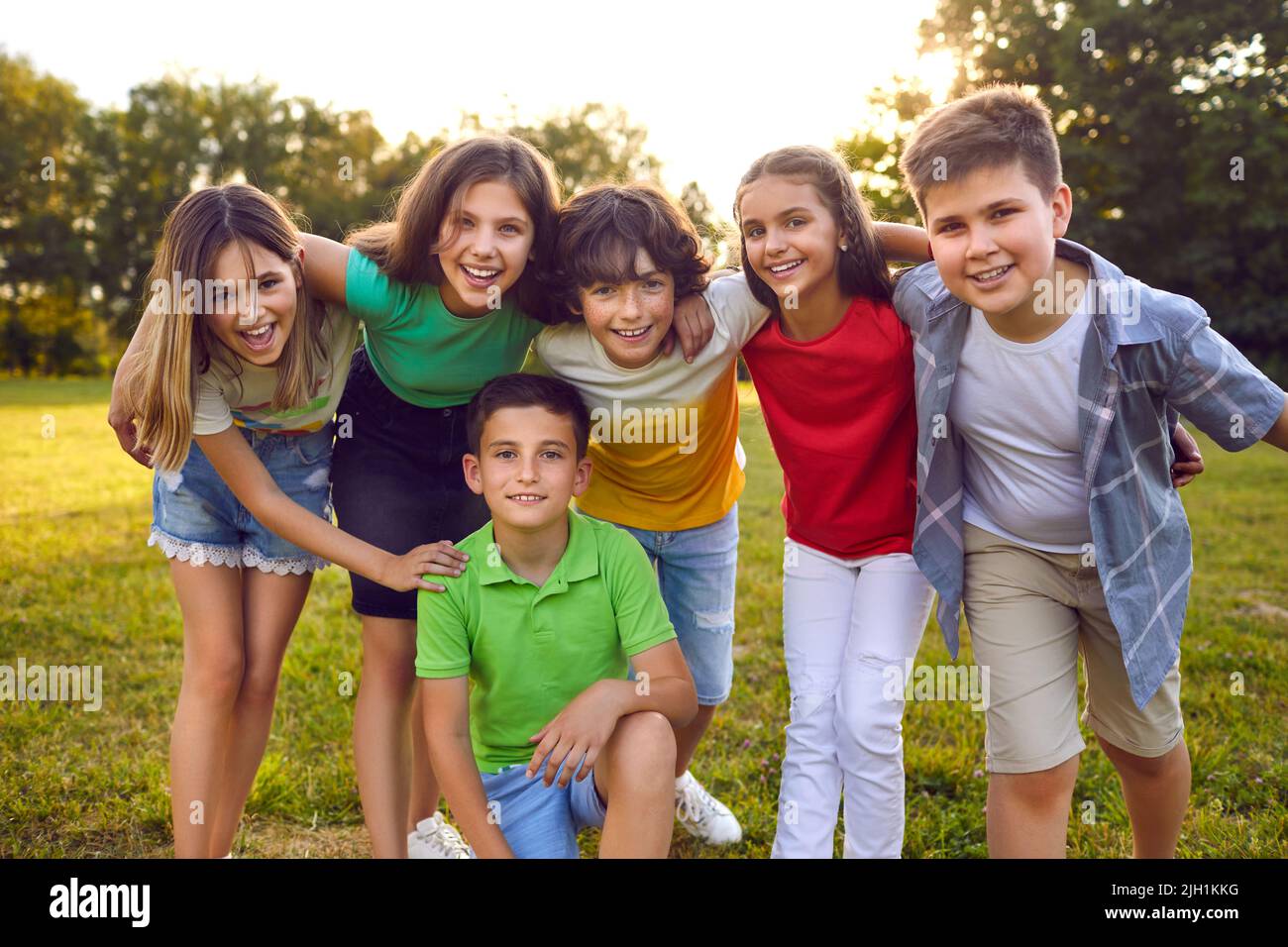 Bunch of cheerful little friends hugging and posing for a group photo in the park Stock Photo