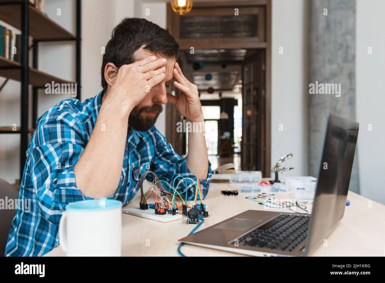 Desperate engineer sitting near laptop Stock Photo