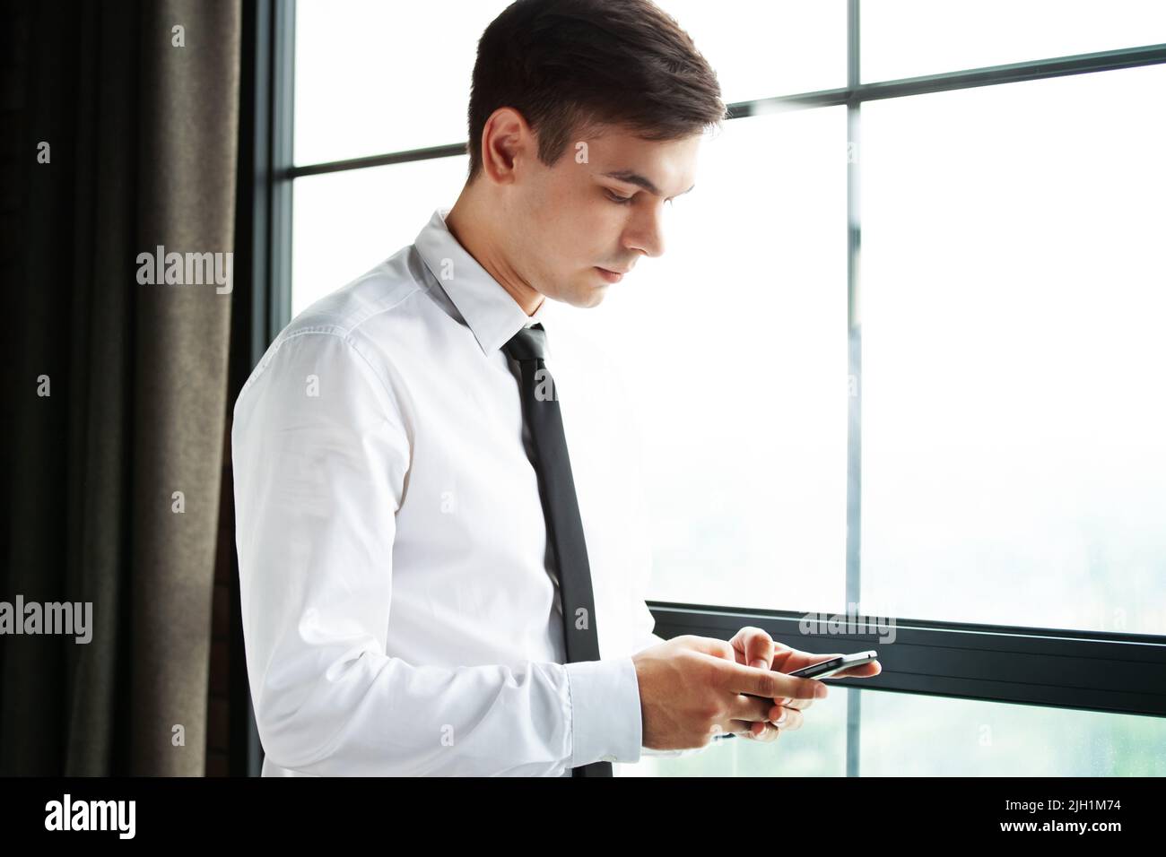 Portrait of a young handsome businessman using his phone. Stock Photo