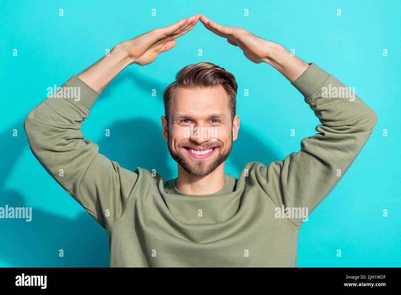 Photo of confident safe man raise hands roof form toothy smile wear pullover isolated blue color background Stock Photo