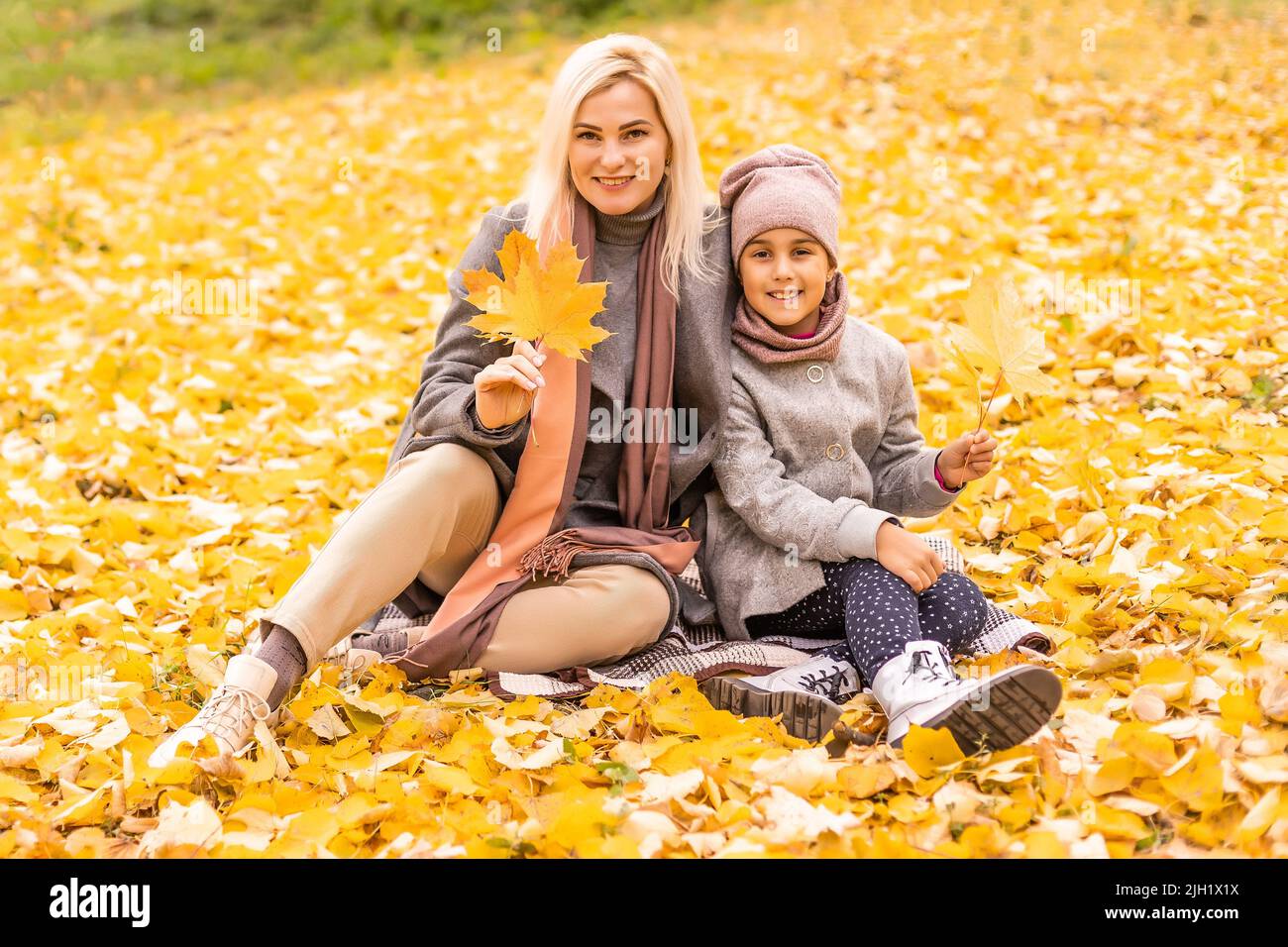 Mother and daughter having fun in the autumn park among the falling ...
