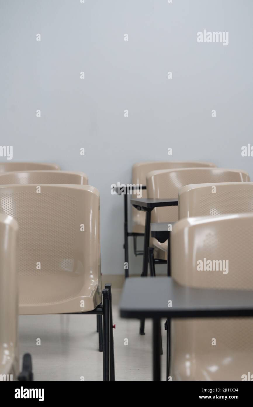 Empty class at university or school with chairs and side table, the chairs are arranged in rows. Stock Photo