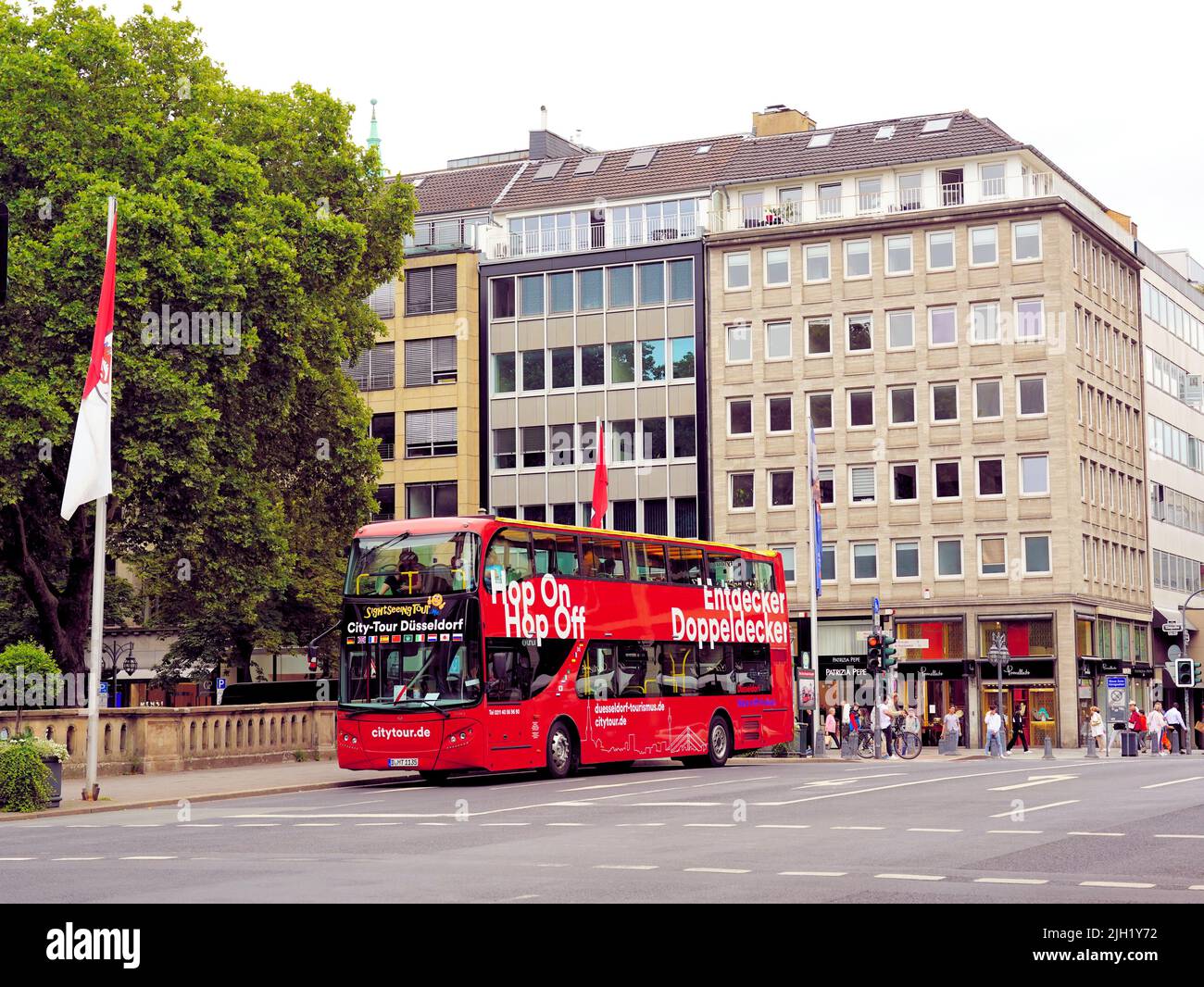 Red doubledecker city tour 'Hop on / Hop off' bus waiting at a stop at Königsallee in a shopping district of Düsseldorf/Germany. Stock Photo