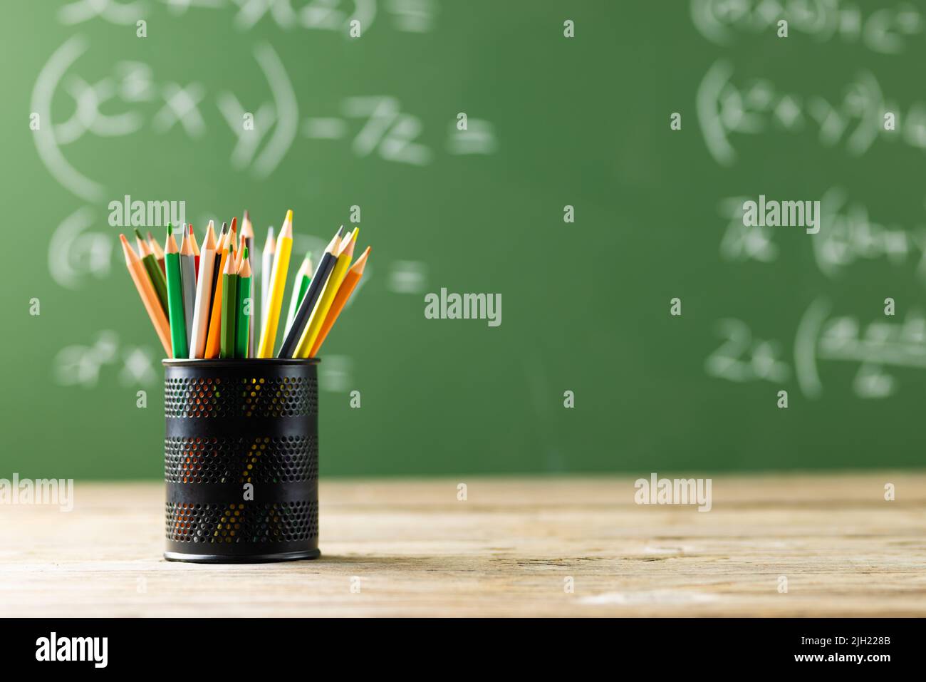 Image of cup with crayons over mathematical formulas on black board Stock Photo