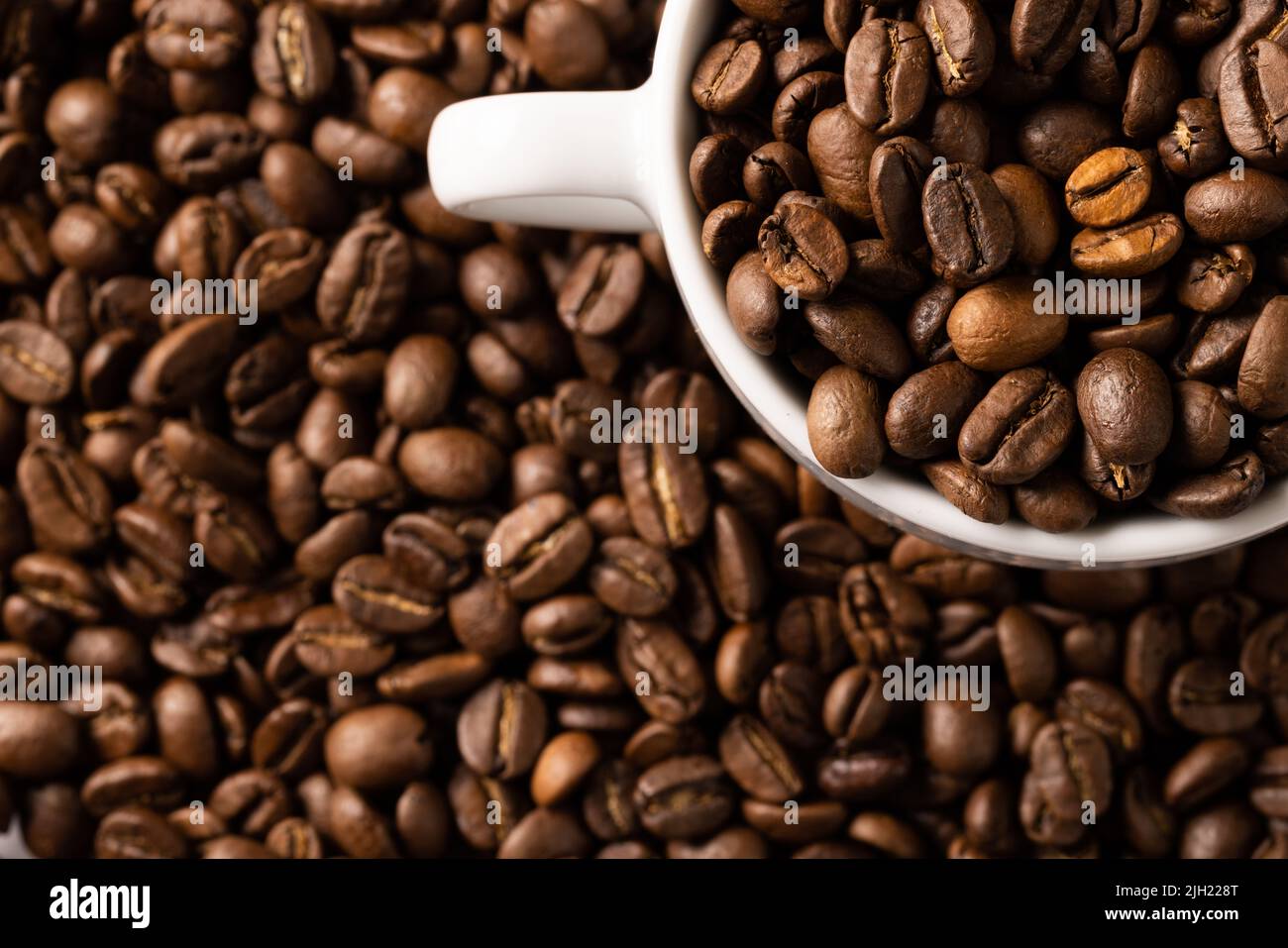 Image of white cup full of coffee beans on pile of coffee beans Stock Photo