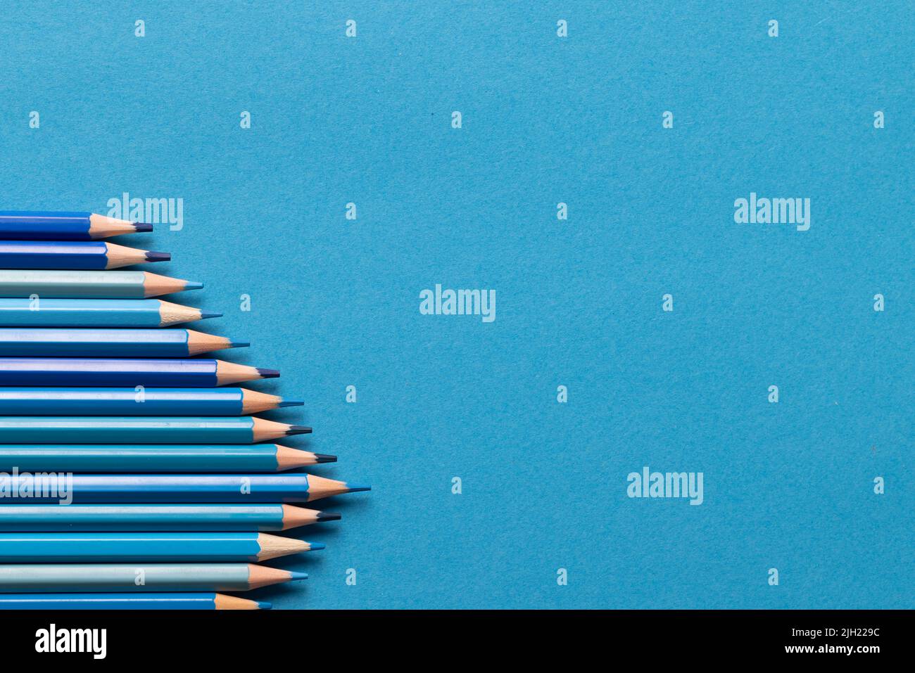 Image of row of different shades of blue crayons on blue background Stock Photo