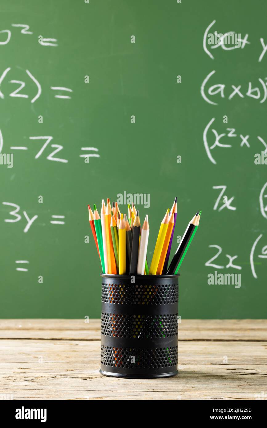 Image of cup with crayons over mathematical formulas on black board Stock Photo