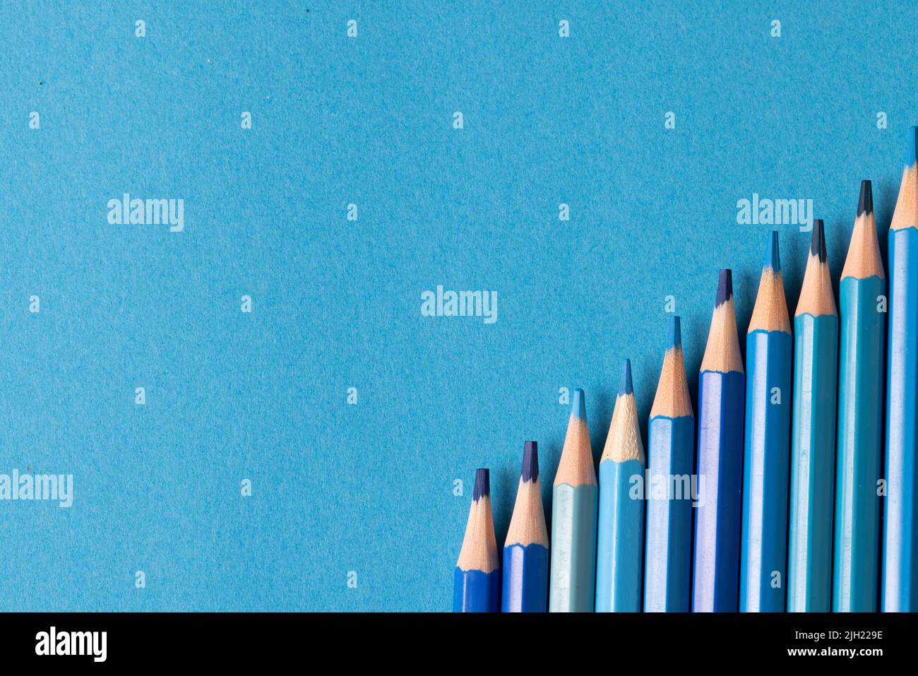 Image of row of different shades of blue crayons on blue background Stock Photo