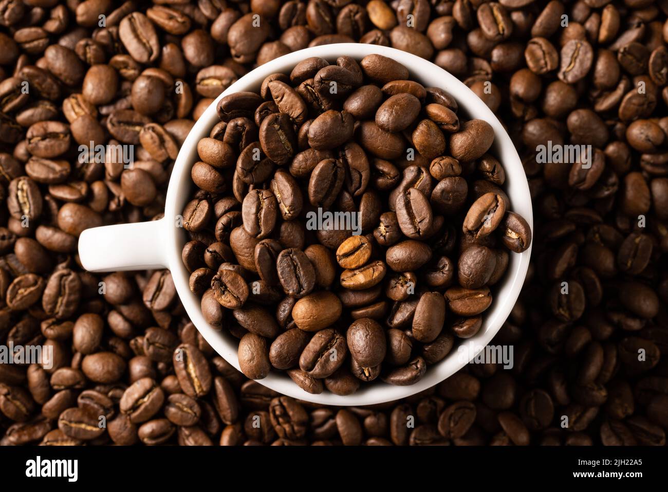 Image of white cup full of coffee beans on pile of coffee beans Stock Photo