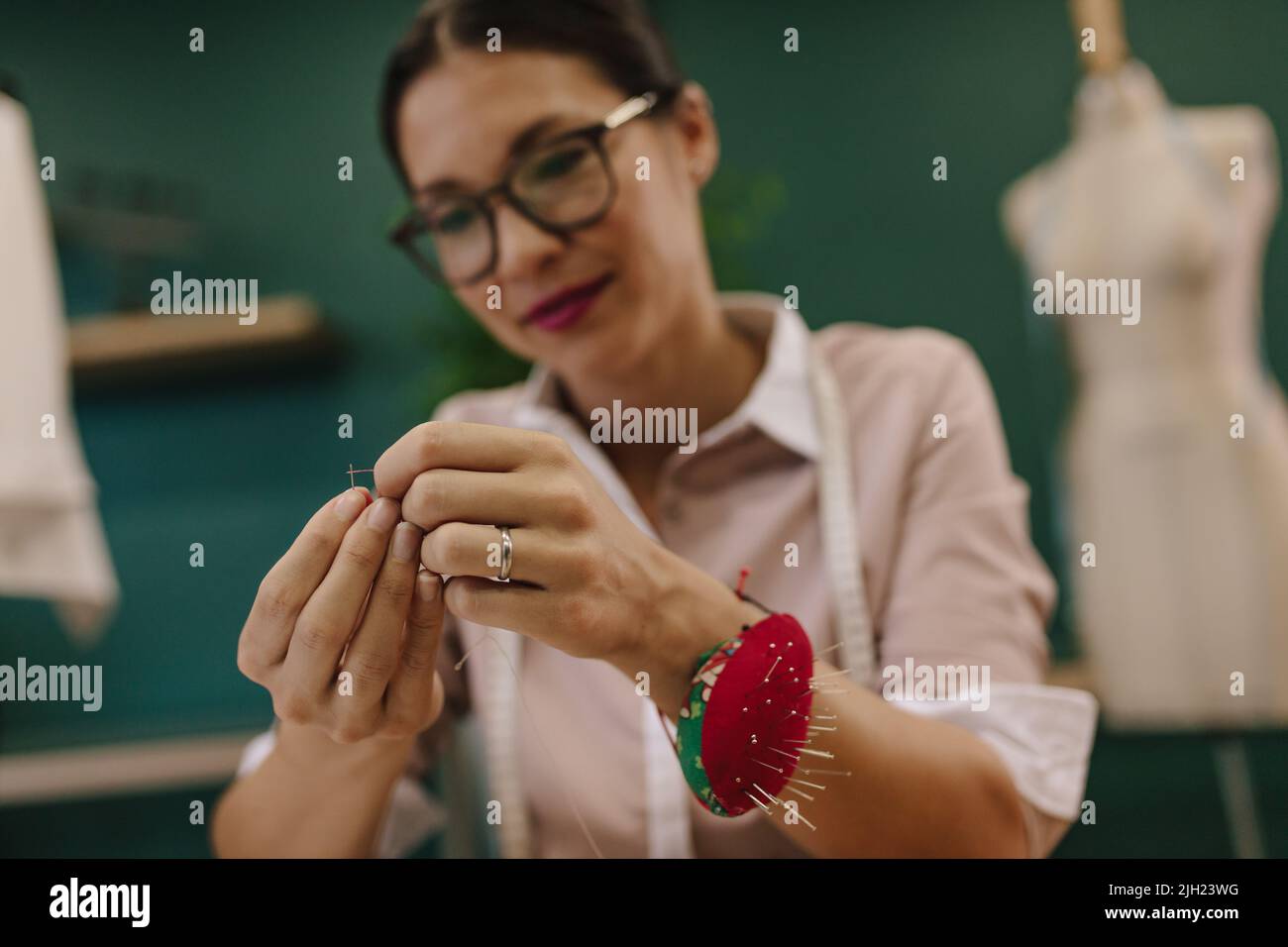 hand threading a needle with black thread Stock Photo - Alamy