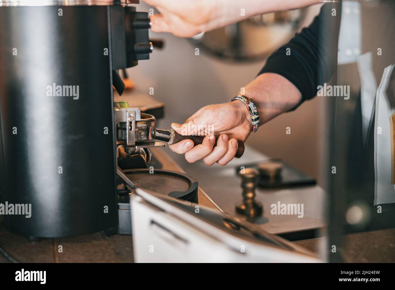 Barista grinds coffee beans pouring into a portafilter using coffee