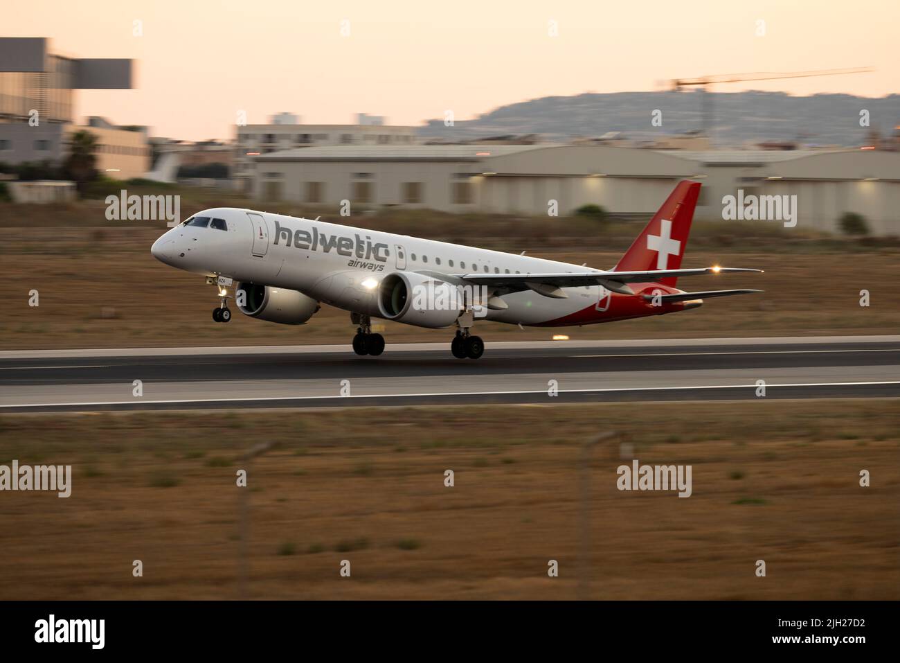 Helvetic Airways Embraer 190 E2 STD (ERJ-190-300STD) (REG: HB-AZA) taking off from 13 after sunset. Stock Photo