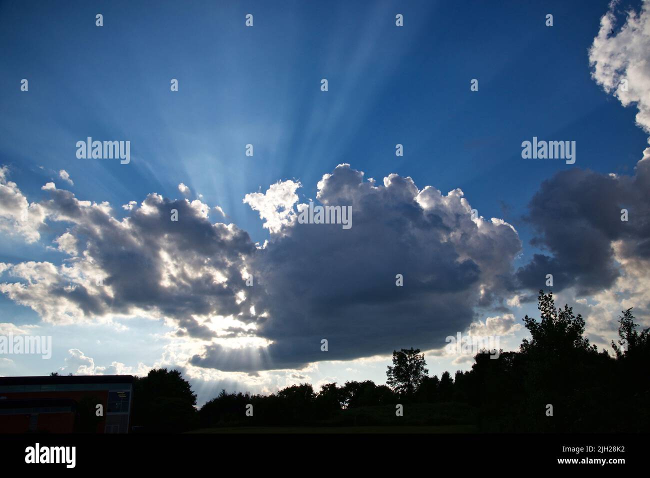 Sun rays with the blue cloudy sky in the background Stock Photo